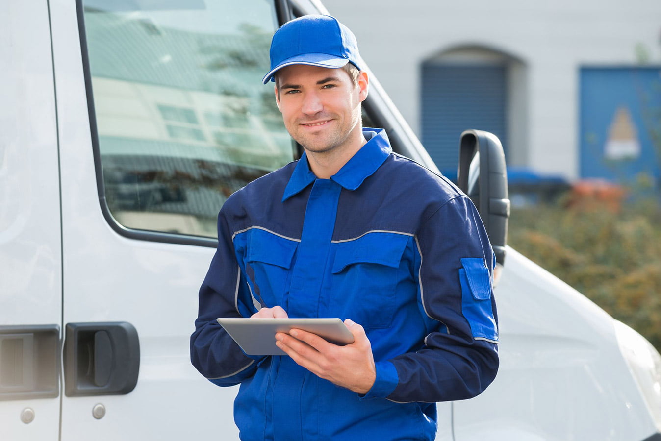 A man holding a tablet in front of a van, potentially engaged in delivery service.