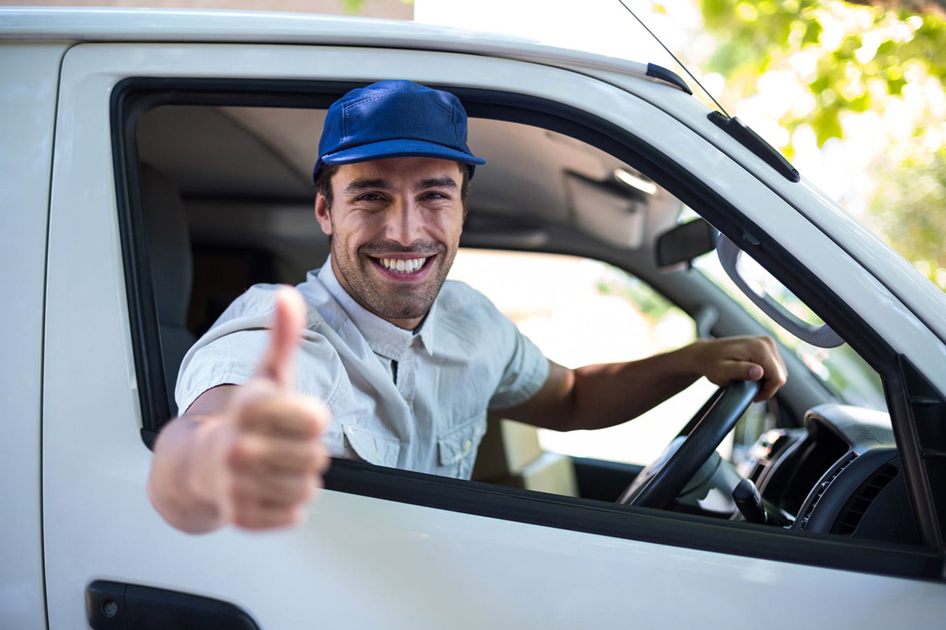 A man giving a thumbs up in the driver's seat of a white van, potentially representing the positive experience of delivery service jobs.