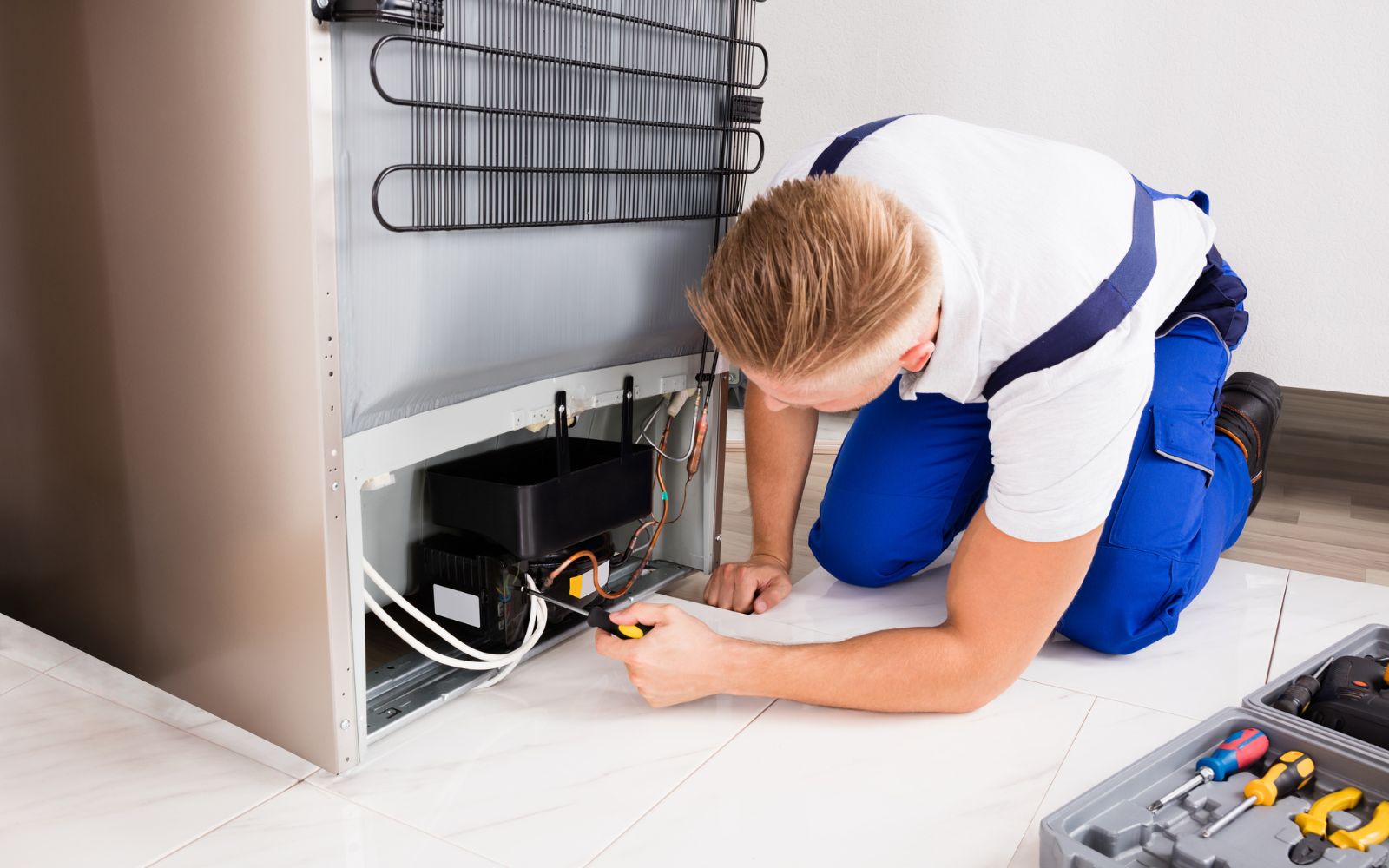 A man using appliance movers to fix a heavy refrigerator in a kitchen.